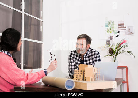 Sorridente colleghi seduti a tavola in un ufficio dell'architetto Foto Stock