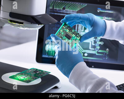 Ingegnere usando un 3D stereo microscopio per il controllo della qualità nella fabbricazione di pannelli di circuito per l'industria elettronica Foto Stock