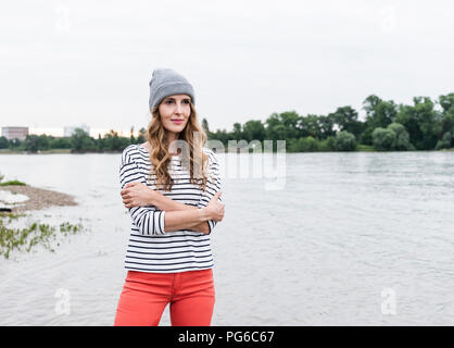 Ritratto di donna che indossa wooly hat permanente al Riverside Foto Stock