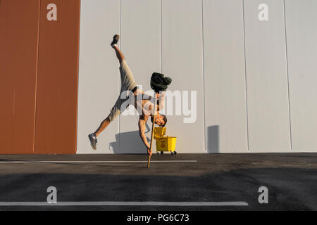 Acrobat giocando con il cucchiaio per la pulitura e la radazza Foto Stock