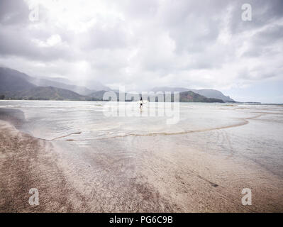 Stati Uniti d'America, Hawaii, Kauai, Hanalei Bay Resort, l uomo sulla spiaggia con la tavola da surf Foto Stock