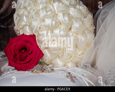 Sposa bouquet con velo, red rose, gli anelli di nozze & croce sul ring del portatore cuscino Foto Stock