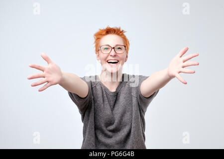 Benvenuti o bello incontrare di concetto. Donna europea in maglione grigio e occhiali con mani stirata handshake. Foto Stock