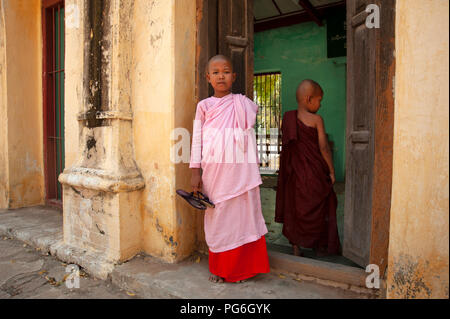 Molto giovane monaca buddista che indossa il rosa e piccolo novizio buddista boy monaco in piedi all'ingresso di una corsa verso il basso edificio templare di Bagan Myanmar Foto Stock