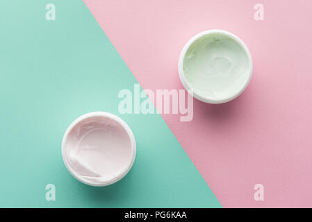 Vista dall'alto di bottiglie di crema sulla rosa e superficie verde, concetto di bellezza Foto Stock