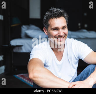 Uomo sorridente in pigiama a casa seduti Foto Stock