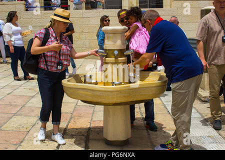 10 maggio 2018 pellegrini ebraica di lavaggio e di bere ad un rubinetto di acqua tra la folla e i turisti presso l'antico Muro Occidentale di Gerusalemme Foto Stock