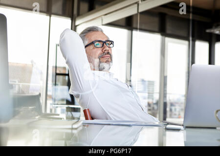 Uomo d affari con computer portatile alla scrivania in ufficio pensando Foto Stock