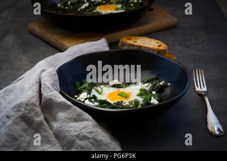 Ciotola di Shakshouka verde con baby spinat, bietole, cipolline e basilico Foto Stock