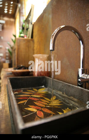 Il lavandino del bagno e acciaio inossidabile tocca nel bagno con acciaio Corten rivestimento a parete Foto Stock
