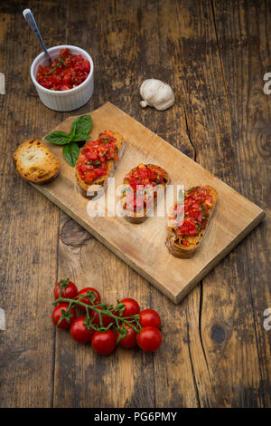 Bruschetta con pomodoro e basilico sul pannello di legno Foto Stock