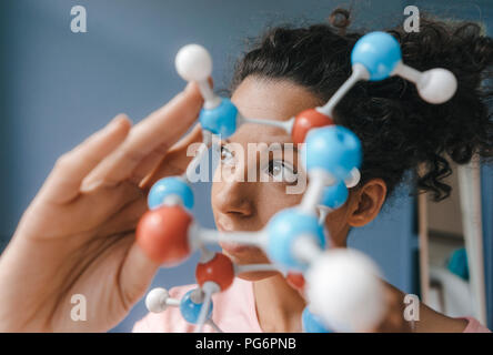 Donna scienziato azienda modello di molecola, cercando soluzioni Foto Stock