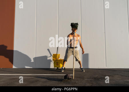 Acrobat giocando con il cucchiaio per la pulitura e la radazza Foto Stock