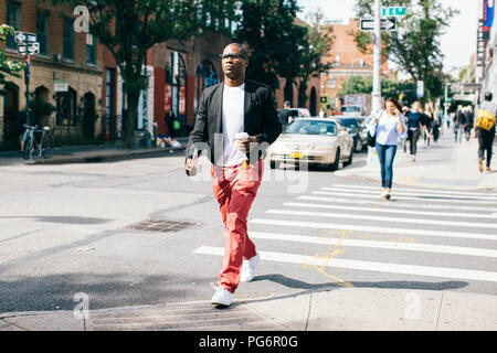 Stati Uniti d'America, New York, Brooklyn, uomo a camminare per la strada, tenendo tazza di caffè Foto Stock