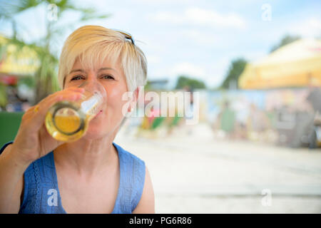 Ritratto di donna senior di bere birra presso il bar sulla spiaggia Foto Stock