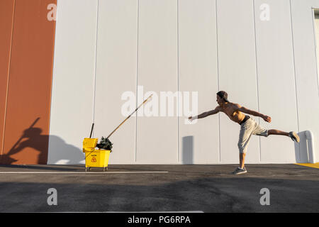 Acrobat giocando con il cucchiaio per la pulitura e la radazza Foto Stock
