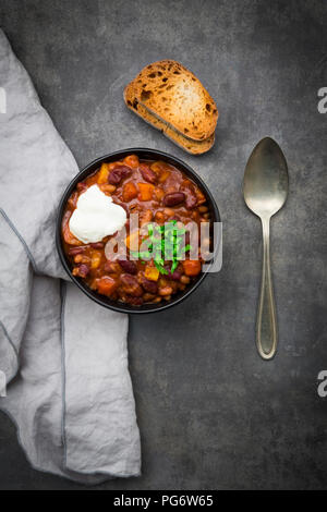Ciotola di Chili con carne con il coriandolo fresco e panna acida Foto Stock