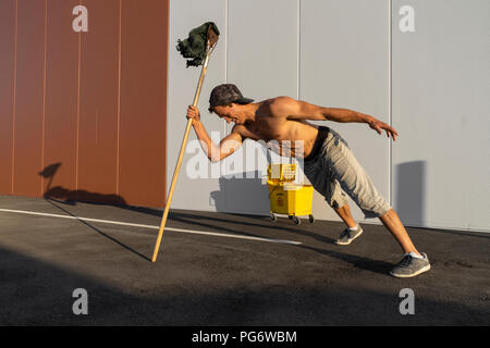 Acrobat giocando con il cucchiaio per la pulitura e la radazza Foto Stock