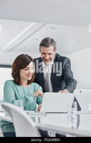 Imprenditore e imprenditrice avente una riunione in ufficio con computer portatile Foto Stock