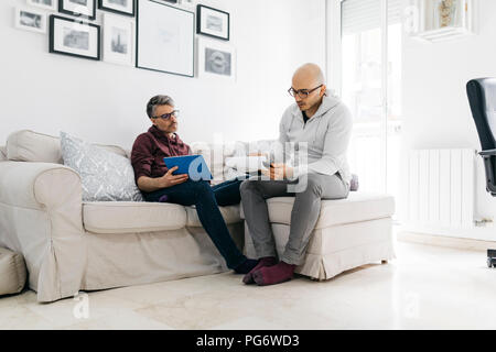 Due colleghi a lavorare su documenti nel salotto di casa Foto Stock