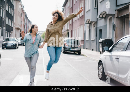 Migliori amici divertendosi in città, in esecuzione a jumping Foto Stock