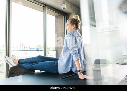 Giovane imprenditrice seduta sulla scrivania Foto Stock