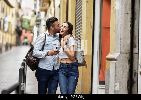 Felice turista giovane con un telefono cellulare a camminare in città Foto Stock