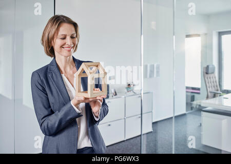 Sorridente imprenditrice guardando al modello architettonico in office Foto Stock