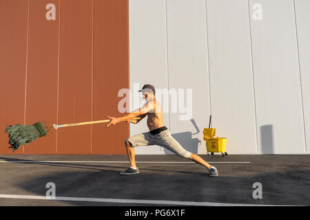 Acrobat giocando con il cucchiaio per la pulitura e la radazza Foto Stock