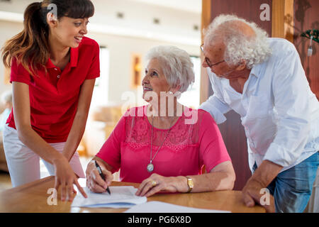 Senior donna firma un contratto, infermiere e senior uomo aiutando il suo Foto Stock