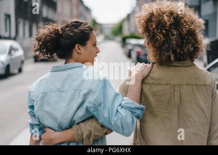 Migliori amici passeggiando nella città, a braccetto, vista posteriore Foto Stock