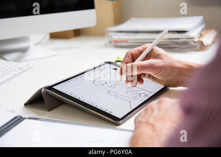 Close-up di uomo che lavora alla scrivania in ufficio disegno figura femminile su tablet Foto Stock