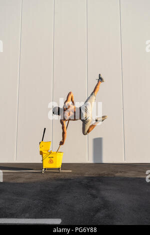 Acrobat giocando con il cucchiaio per la pulitura e la radazza Foto Stock