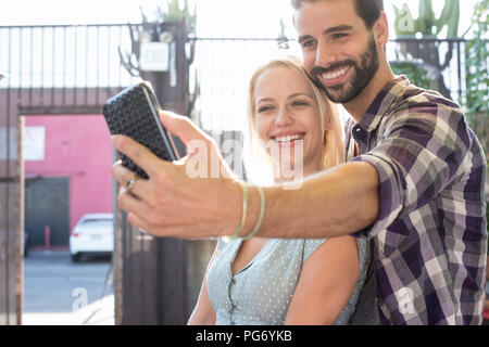 Felice giovane uomo con la fidanzata prendendo un selfie Foto Stock