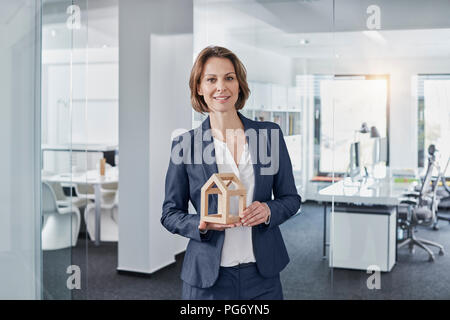 Ritratto di sorridere imprenditrice azienda modello architettonico in office Foto Stock