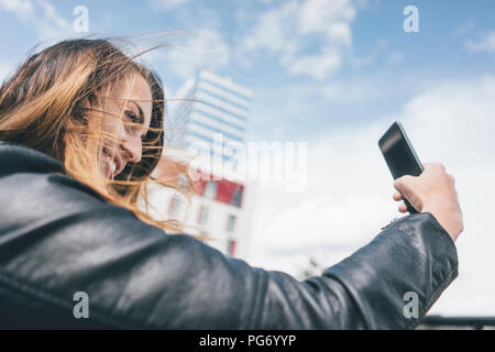 Sorridente giovane donna prendendo un selfie all'aperto Foto Stock