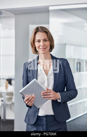 Ritratto di sorridere imprenditrice azienda tablet in ufficio Foto Stock