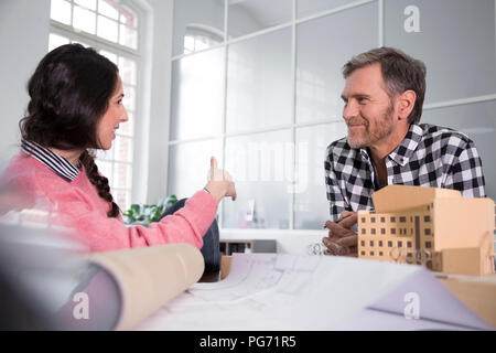 Sorridendo i colleghi a discutere di modello architettonico in office Foto Stock