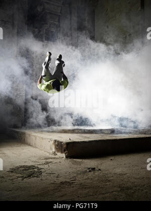 Uomo di saltare in una nube di polvere durante l'esercizio freerunning Foto Stock