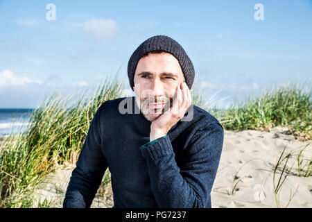 Ritratto di uomo che indossa cappellino sulla spiaggia Foto Stock