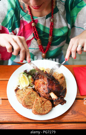 Close-up di donna Schweinshax mangiare nel ristorante di strada Foto Stock