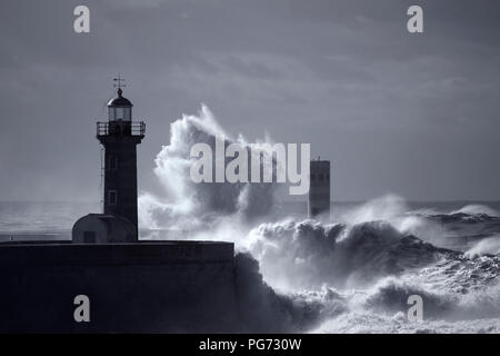 Tempesta di mare vedendo grandi onde che si schiantano contro i pontili, vecchio faro e il faro del fiume Douro bocca, Porto, Portogallo. Utilizzate il filtro a raggi infrarossi. Nei toni del blu. Foto Stock