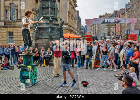 EDINBURGH FESTIVAL FRINGE 2018 gettando un tizzone per un giocoliere equilibratura su grandi bobine di legno Foto Stock