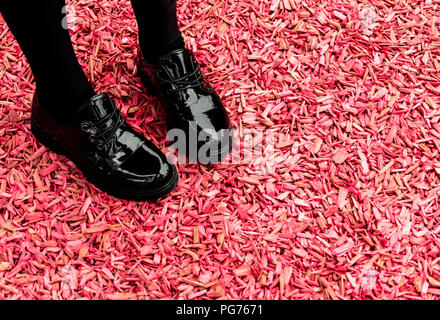 La ragazza lucido nero scarpe rosa sul terreno di truciolo Foto Stock