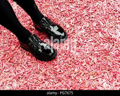 La ragazza lucido nero scarpe rosa sul terreno di truciolo Foto Stock