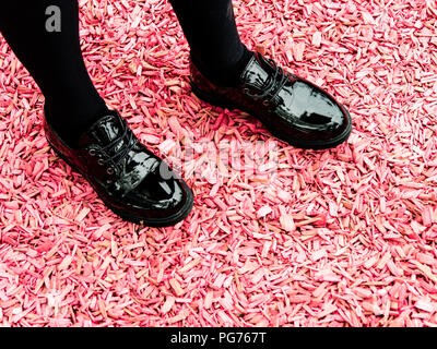 La ragazza lucido nero scarpe rosa sul terreno di truciolo Foto Stock