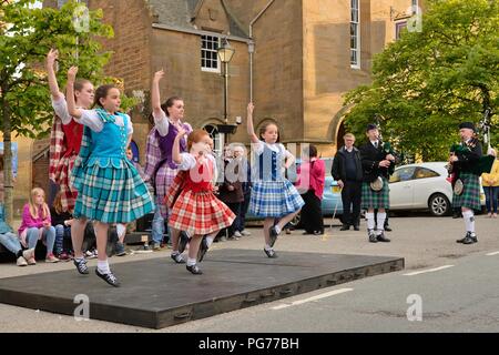 Giovani ballerini scozzesi delle Highland che si esibiscono per i turisti nella piazza principale di Dornoch, Sutherland, Scozia, Regno Unito Foto Stock