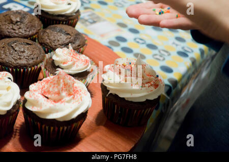 Bambino di topping di irrorazione sui tortini fatti in casa - USA Foto Stock