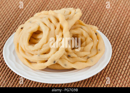 Indian murukku snack - Una macro closeup della tradizionale profondo fritto indiano murukku snack su una piastra. Foto Stock