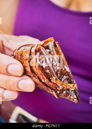 Una femmina la mano che regge un cioccolato Trigona Panoramatos, tipico greco fillo dolce. Foto Stock